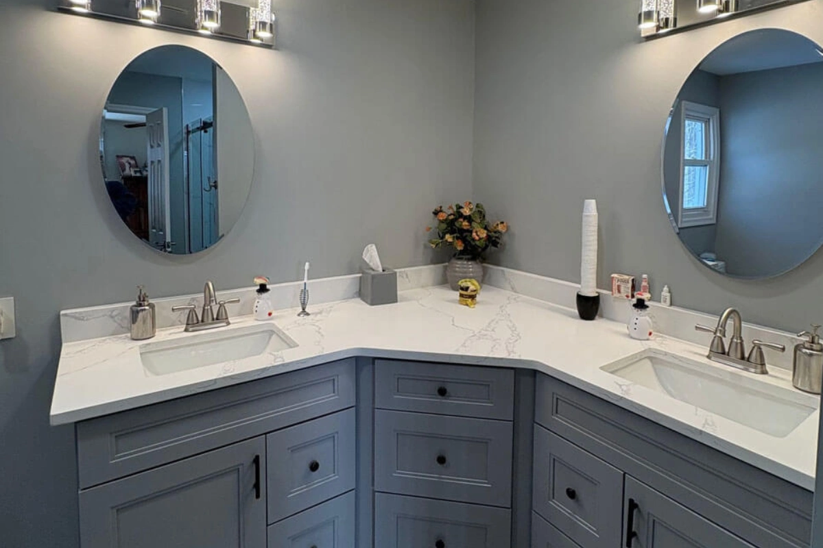 Contemporary Bathroom Remodeling in Sewell NJ showcasing a corner double vanity with soft gray cabinetry, sleek fixtures, and bright overhead lighting creating a stylish and functional space.
