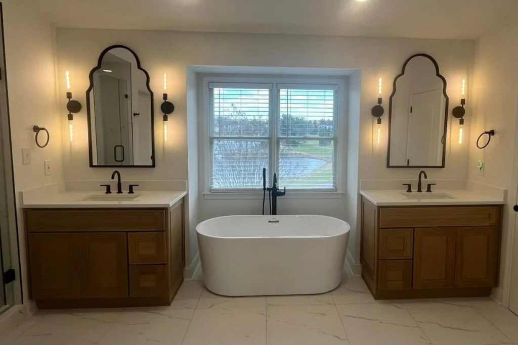 Elegant Bathroom Remodeling in Pitman NJ featuring a freestanding bathtub, double vanities with wood cabinetry, black fixtures, and decorative mirrors for a modern classic look.