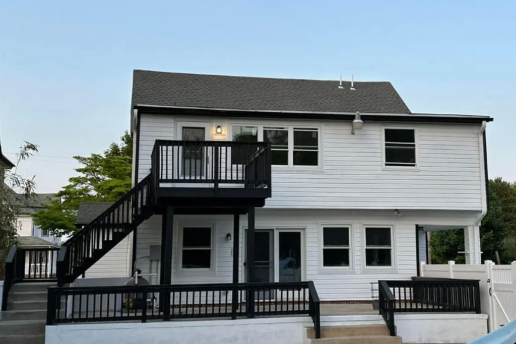 Renovated two-story home with black deck railing and fresh siding completed by a professional General Contractor in Glassboro NJ.