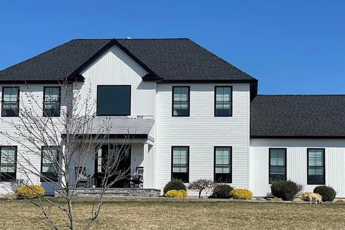 Newly completed roofing replacement on a modern two-story white farmhouse in Washington Township NJ, featuring black asphalt shingles and clean architectural lines under a clear blue sky.