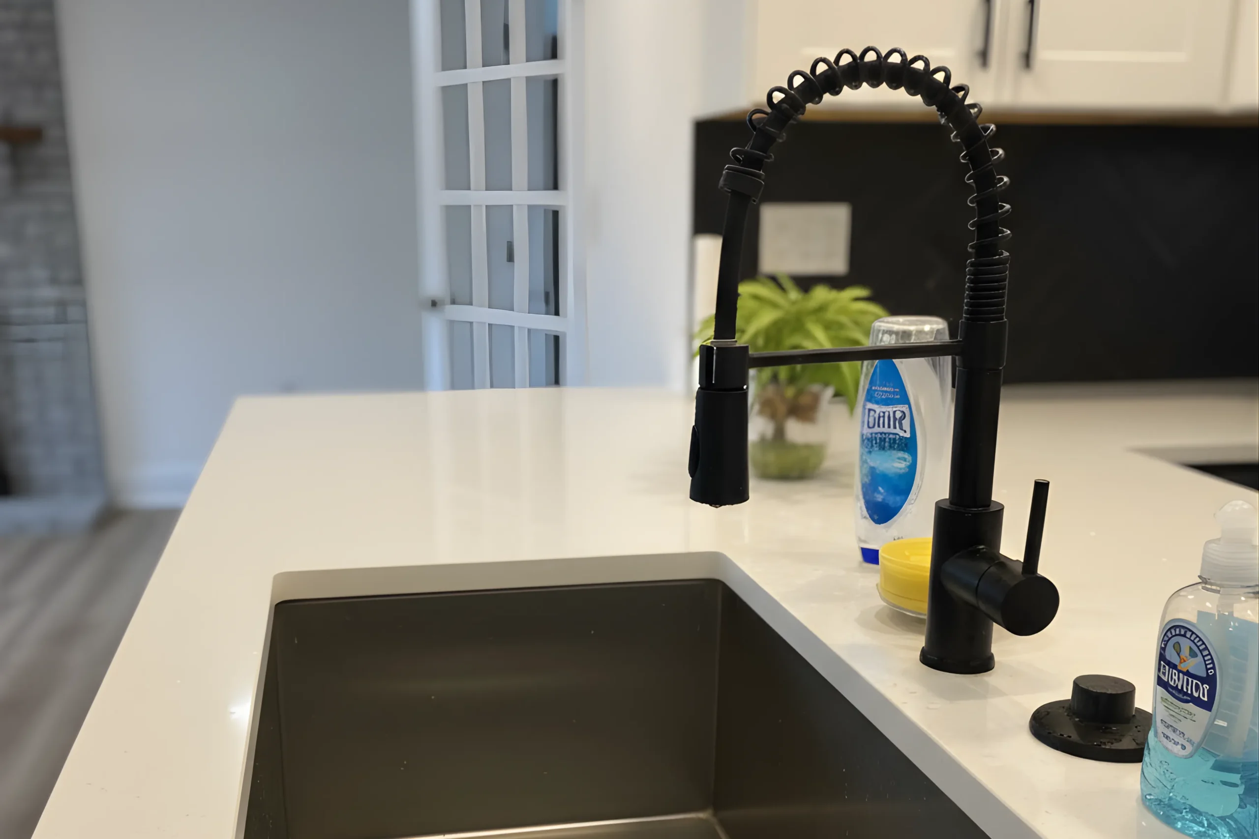 Modern matte black commercial-style spring faucet installed on a white quartz countertop with an undermount sink during a kitchen remodel in Turnersville, NJ.