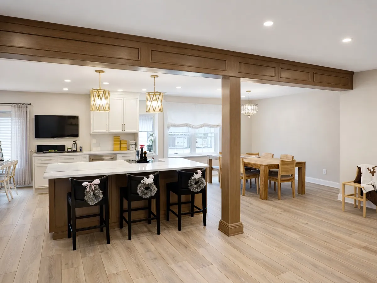 Open first-floor layout with exposed beam, kitchen island, and dining area in Somerton Philadelphia remodel