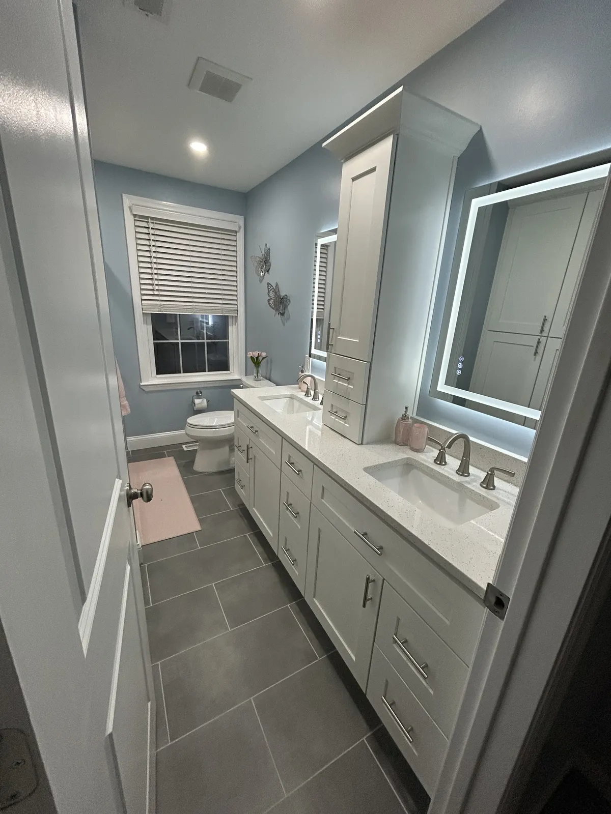 Bathroom remodel in Philadelphia with blue walls, white double vanity, LED mirrors, and slate floor tile