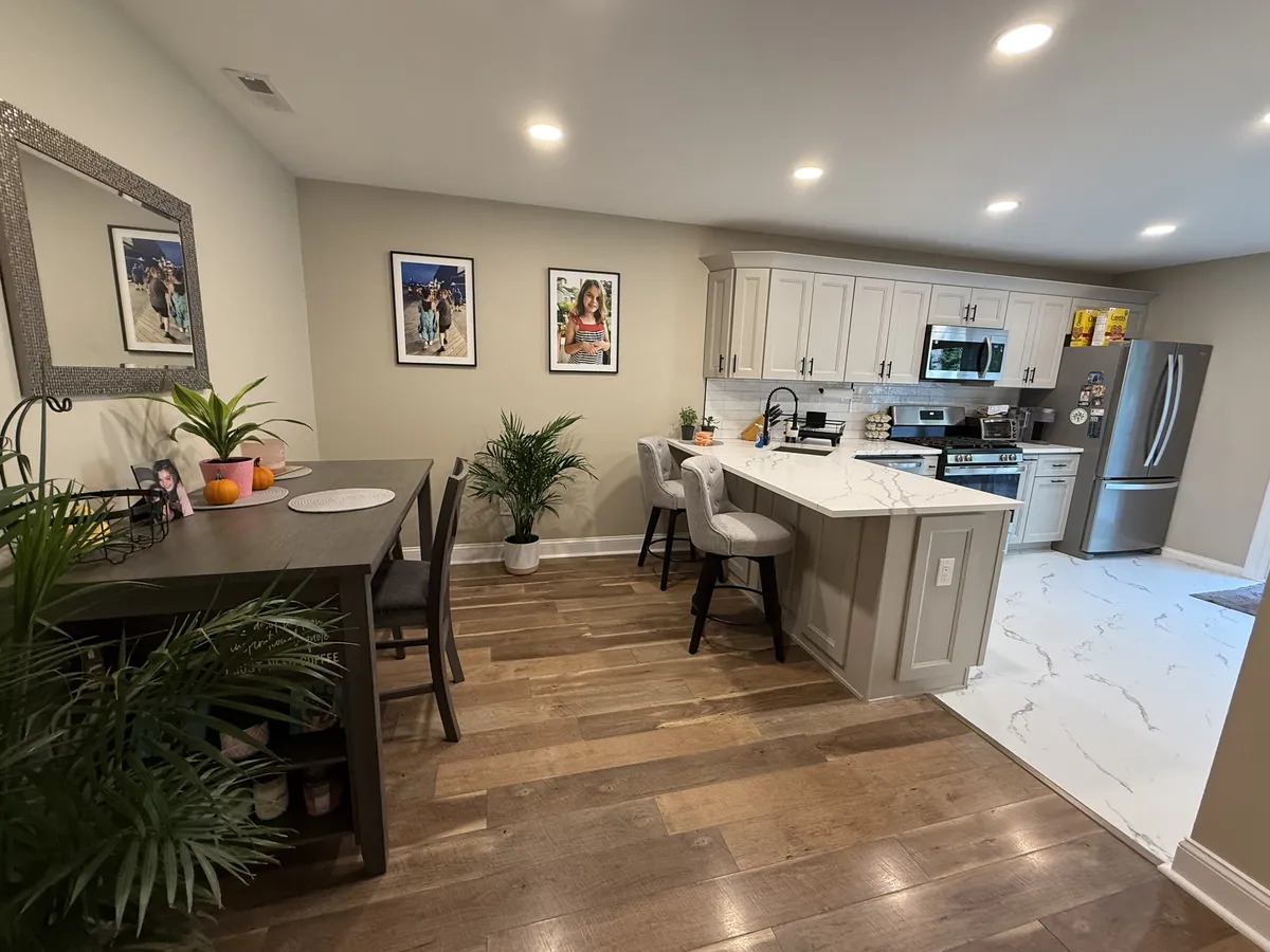 Full kitchen overview from the dining area showing white cabinets, hardwood floors, and dining table in Philadelphia remodel
