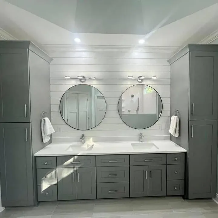 Gray double sink vanity with white countertop and round mirrors by Showcase Remodels