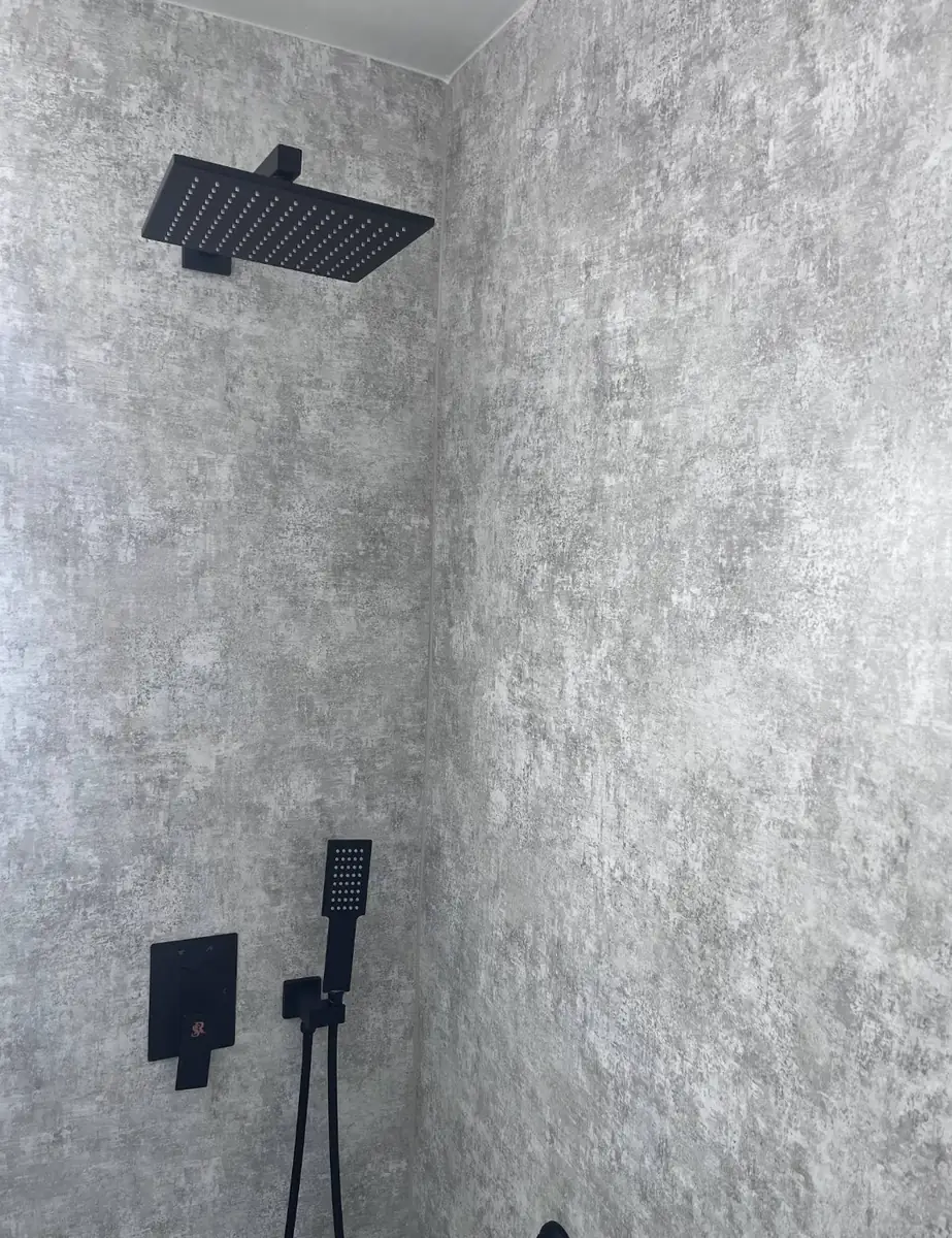 Matte black rain shower head and concrete-look wall panels in a Holmesburg bathroom remodel