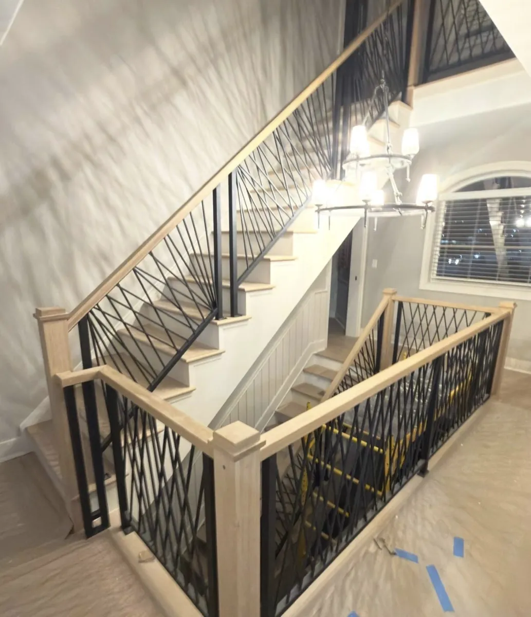 Custom oak staircase with black iron zigzag spindles and matching handrail in a Bustleton home