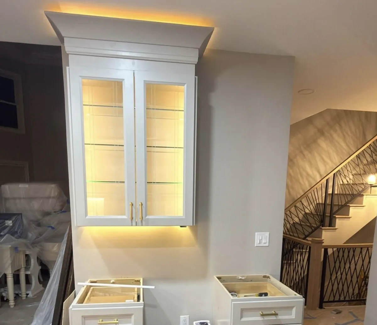 Built-in glass-door display cabinet with warm LED accent lighting in a Bustleton home