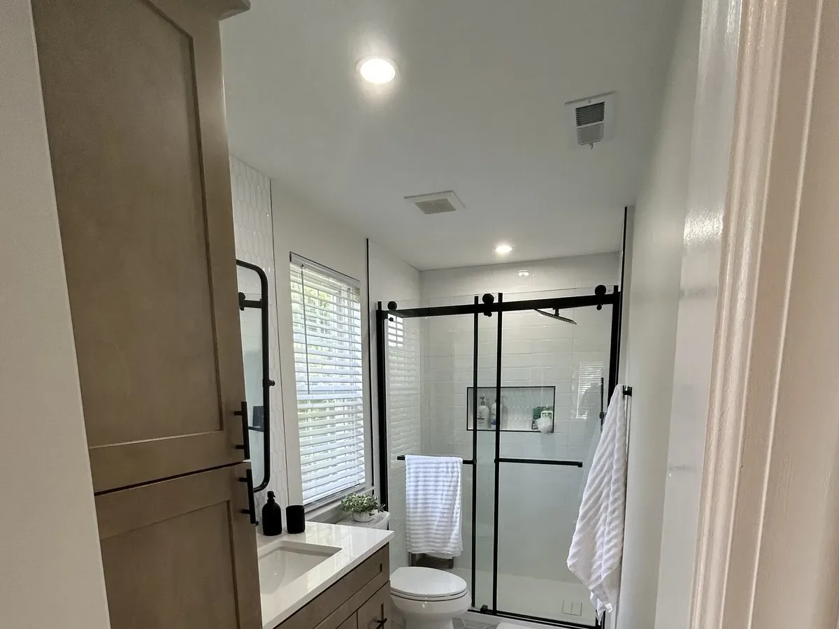 Full bathroom renovation showing wood vanity and glass shower enclosure in Philadelphia