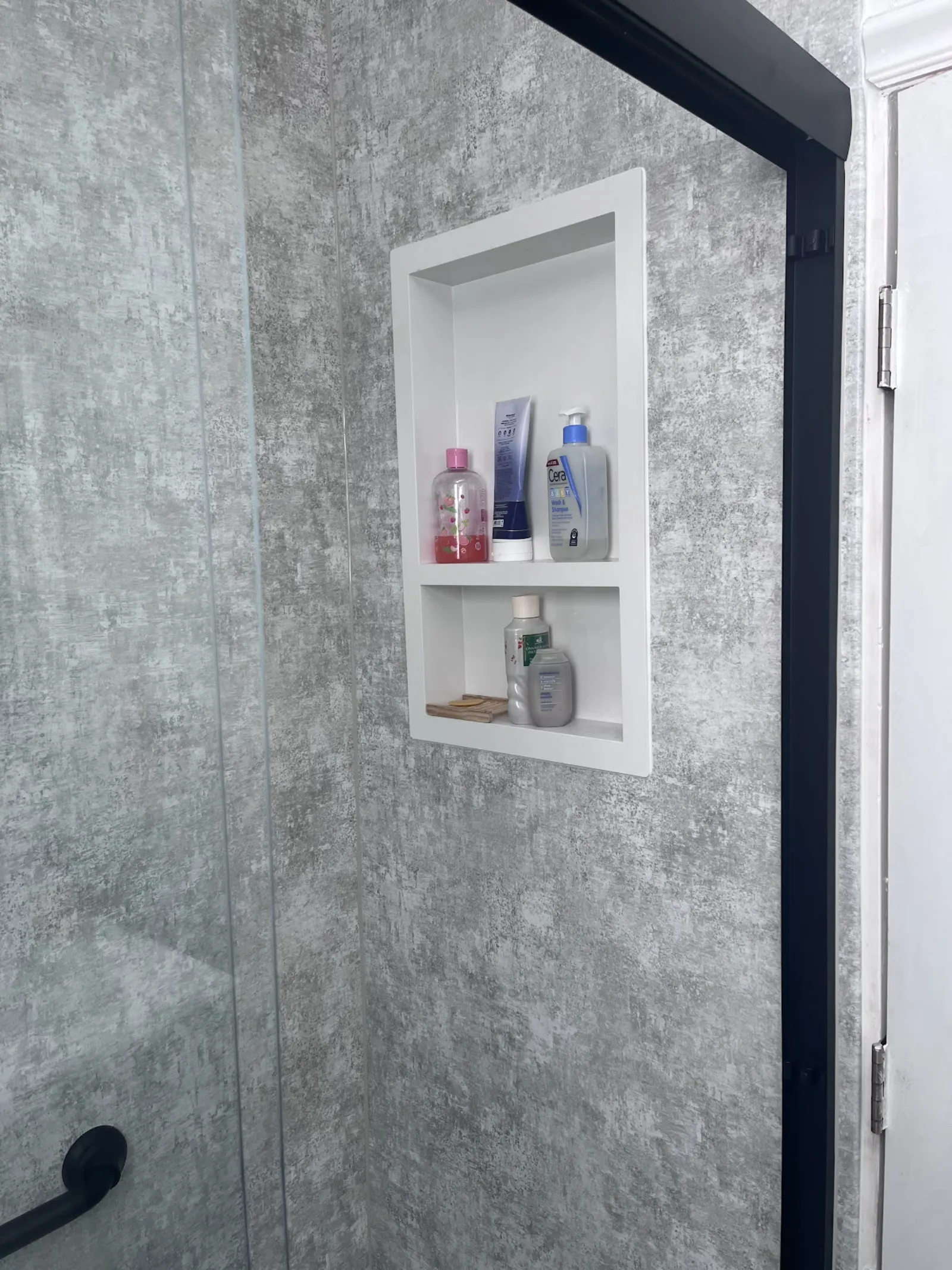 Recessed shower niche with shelves and gray tile inside a remodeled walk-in shower by Showcase Remodels in Philadelphia