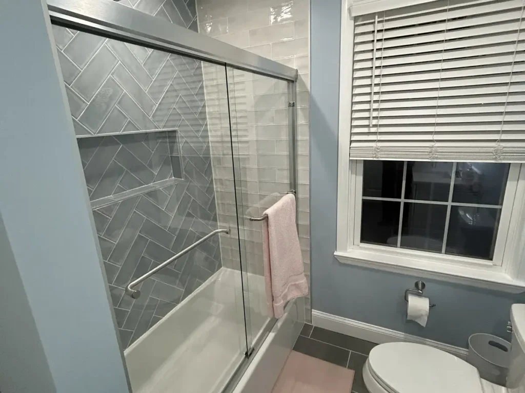 Steam shower with herringbone tile and glass enclosure by Showcase Remodels in Philadelphia
