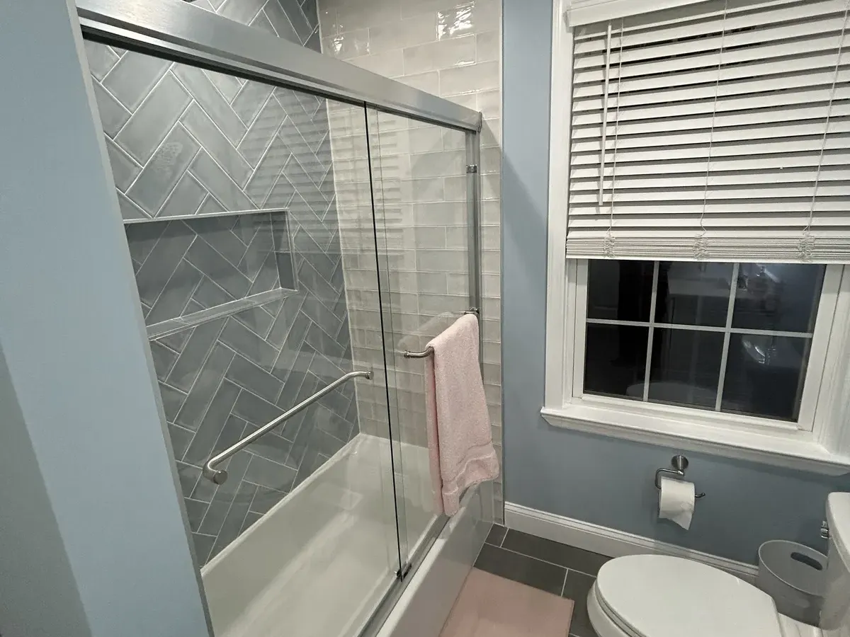 Steam shower with herringbone tile and glass enclosure by Showcase Remodels in Philadelphia