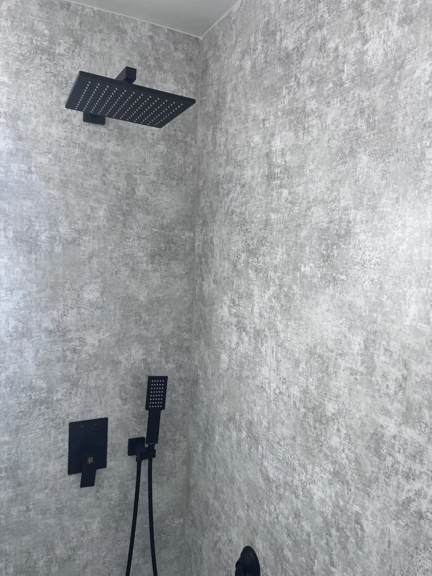 Matte black rainfall showerhead and handheld wand in walk-in shower remodeled by Showcase Remodels in Philadelphia
