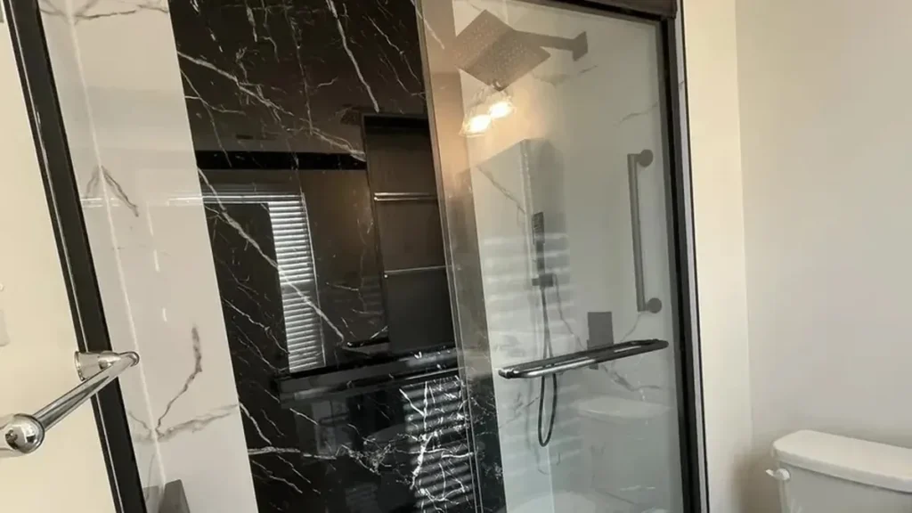 Walk-in shower with black marble tile and sliding glass door installed in Philadelphia home