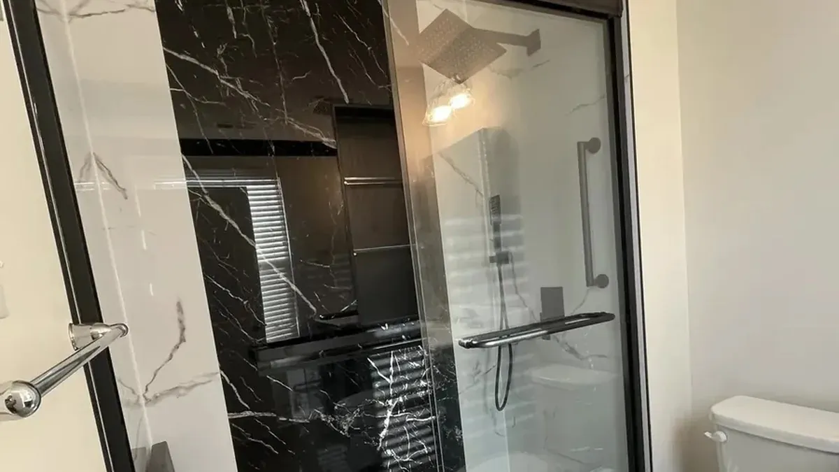 Walk-in shower with black marble tile and sliding glass door installed in Philadelphia home