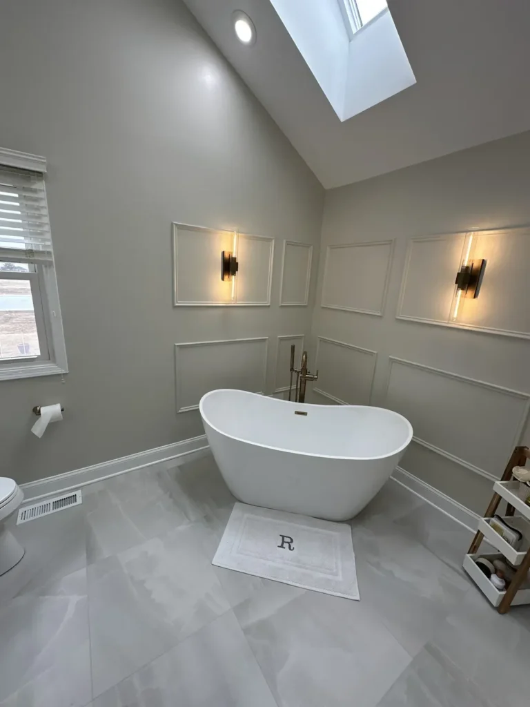 Primary bathroom with a freestanding tub, panel molding, wall sconces and a skylight