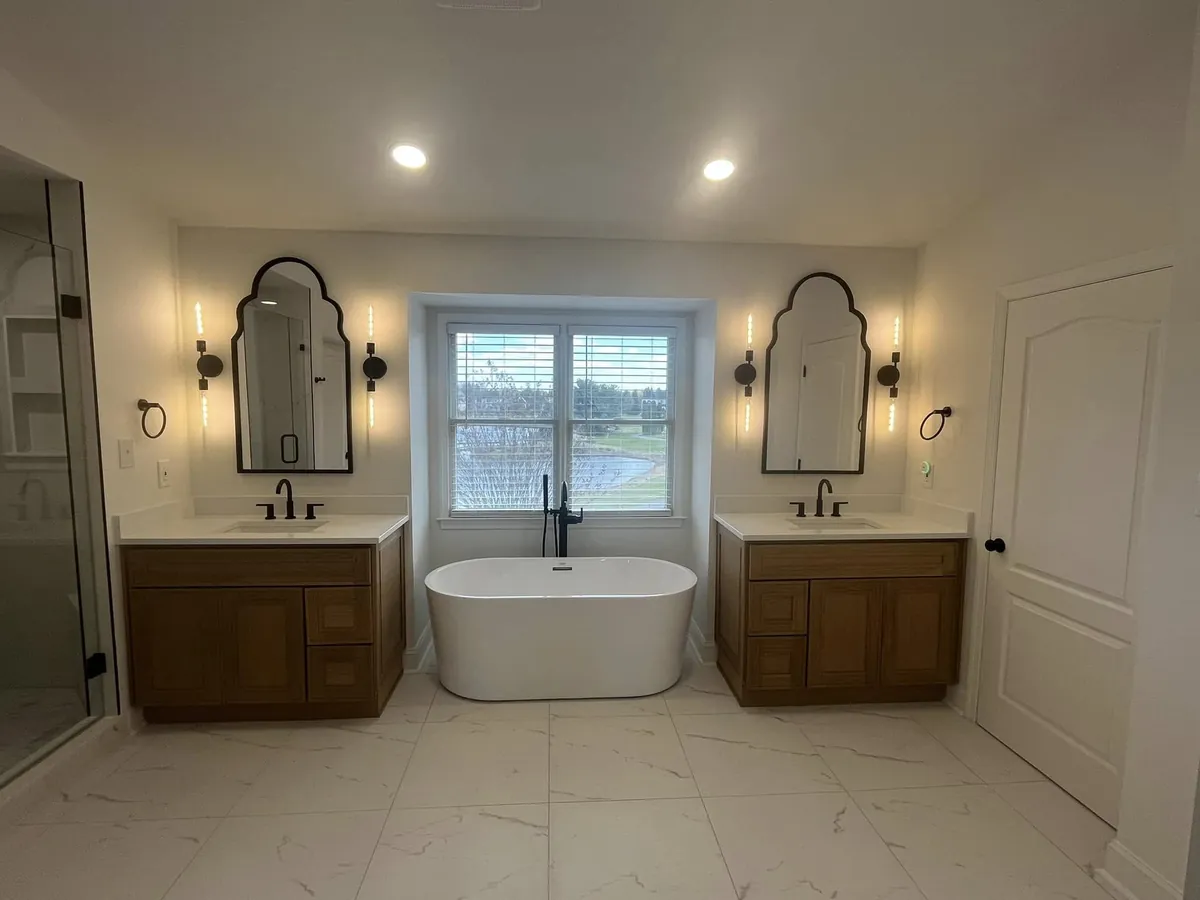 Two wood vanities flanking a freestanding tub under a window in Franklinville, Philadelphia