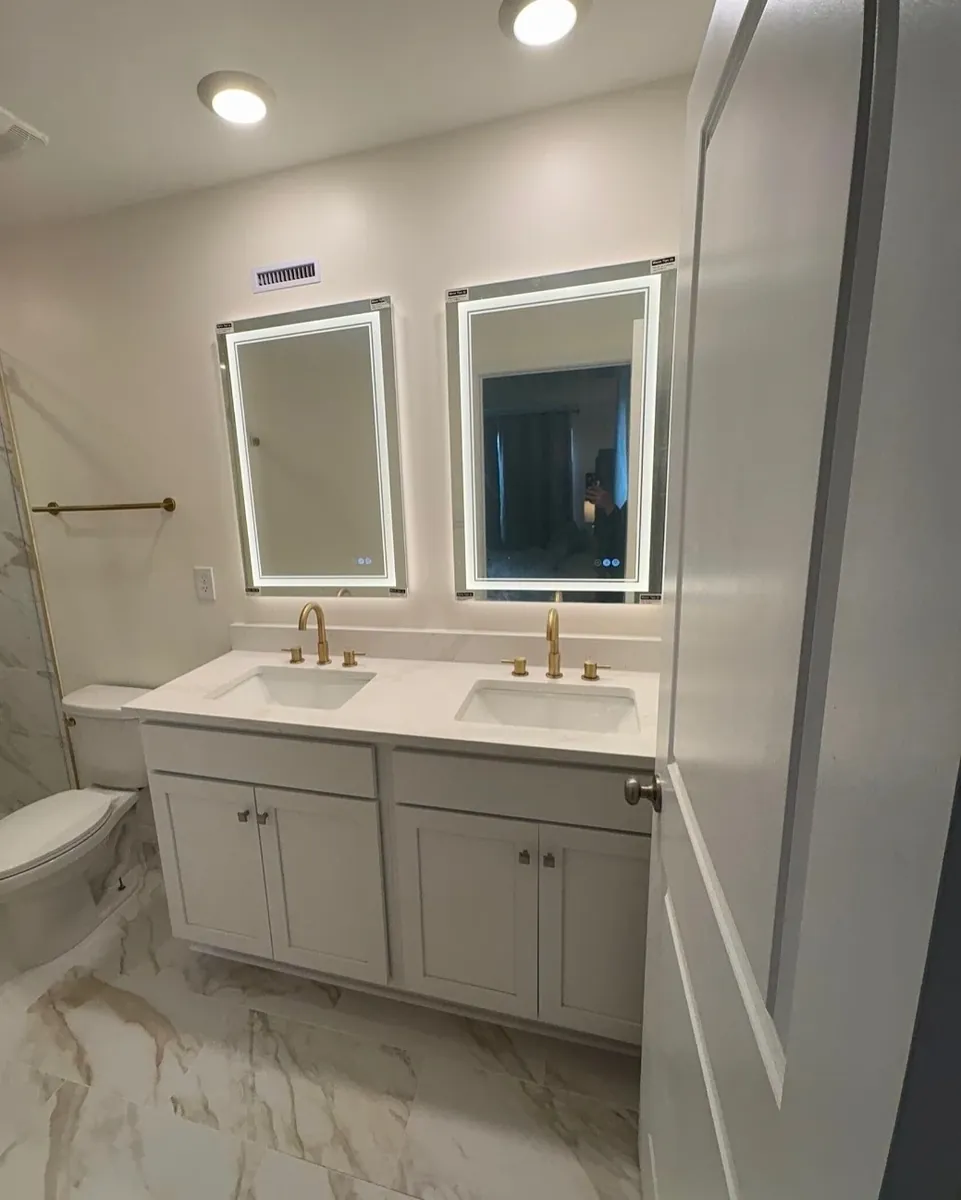 White double vanity with lit mirrors and gold faucets in Juniata Park, Philadelphia