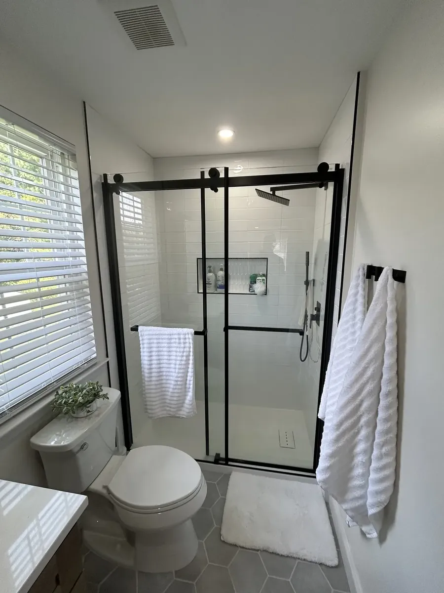 Black-frame shower stall lined with white subway tile in Mantua, Philadelphia