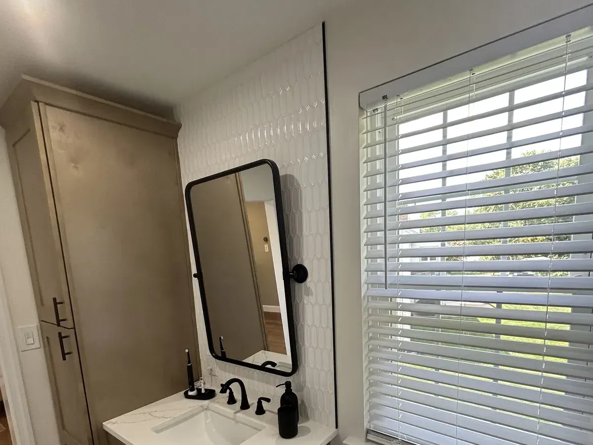 Single wood vanity with black fixtures beside wide blinds in Mantua, Philadelphia