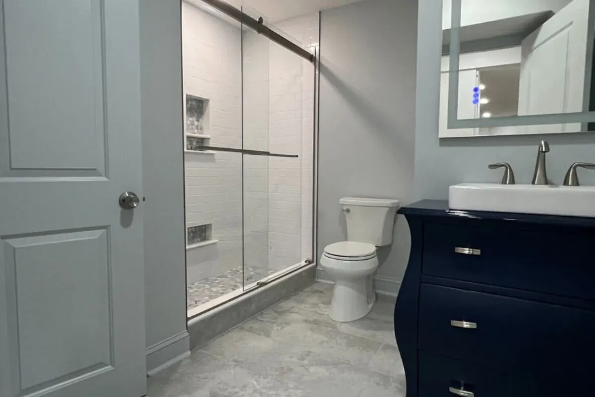 Sliding glass shower door beside a navy vanity in General Pulaski Park, Philadelphia