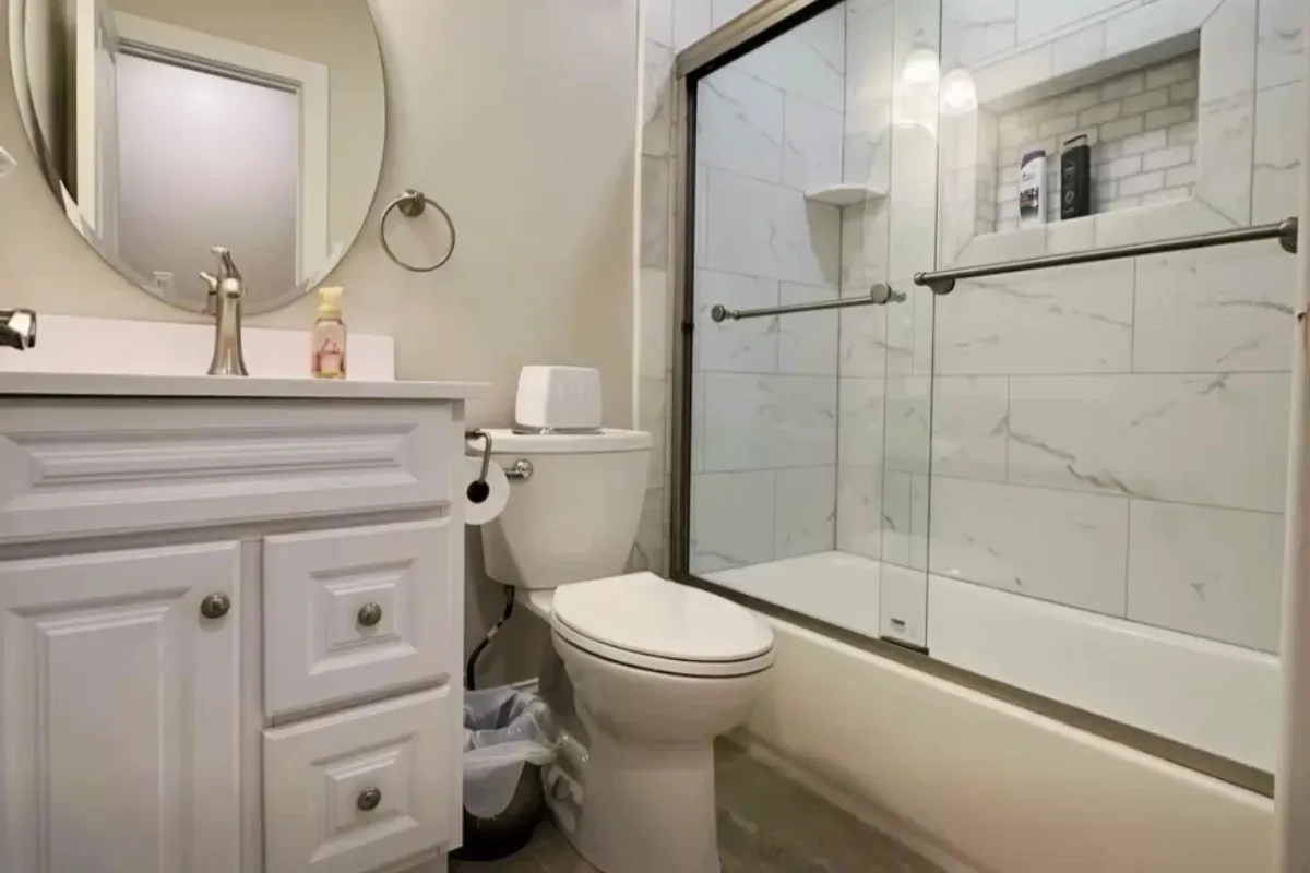 White vanity with a marble tub shower and arched mirror in General Pulaski Park, Philadelphia