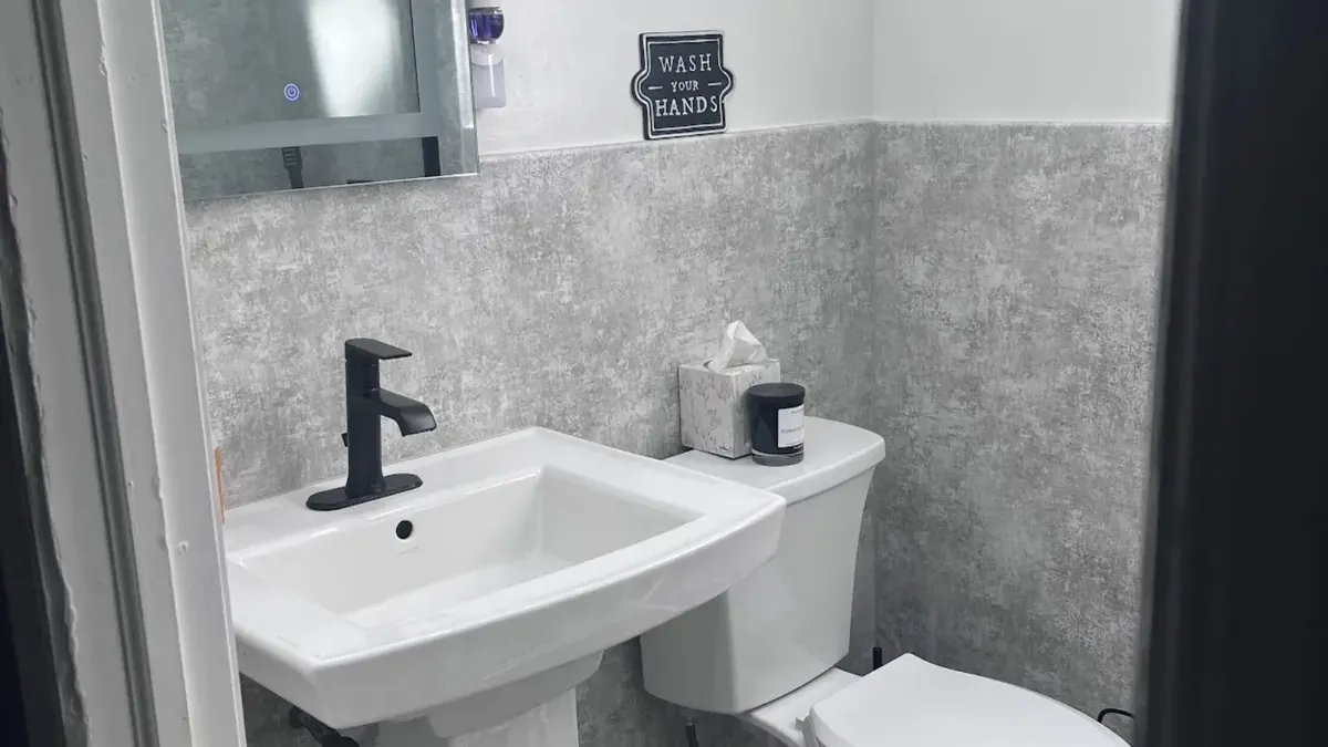 Powder room sink set against stone-look wall panels in Port Richmond, Philadelphia