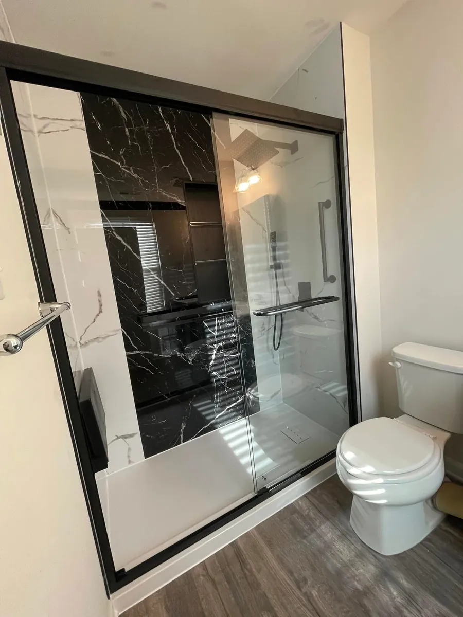 Black marble-look shower with a glass slider and grab bar in Sharswood, Philadelphia