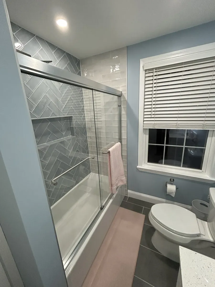 Tub shower with gray herringbone tile beside a window in Sharswood, Philadelphia