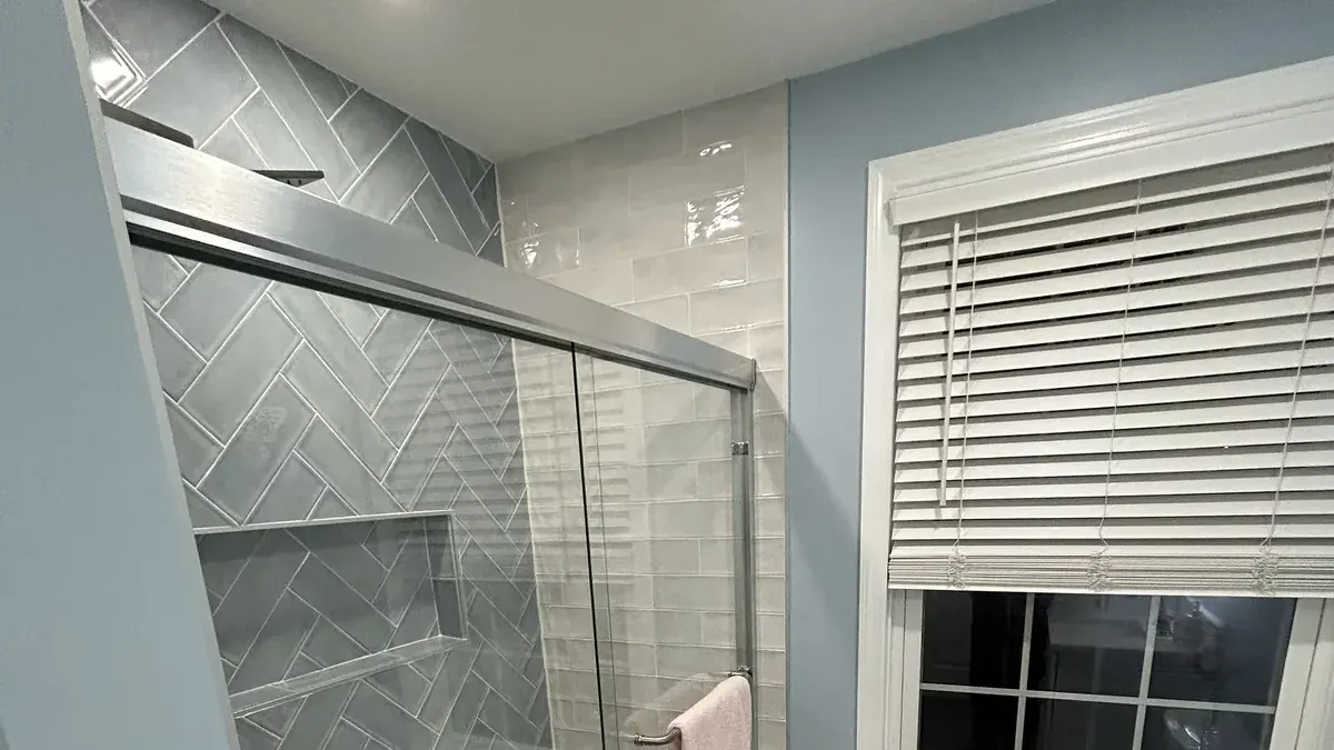 Herringbone tile shower wall behind a clear glass door in Spring Garden, Philadelphia