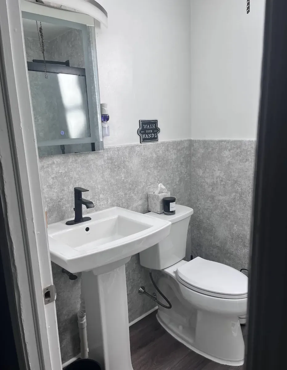 Powder room with a black faucet and gray wainscot panels in Strawberry Mansion, Philadelphia