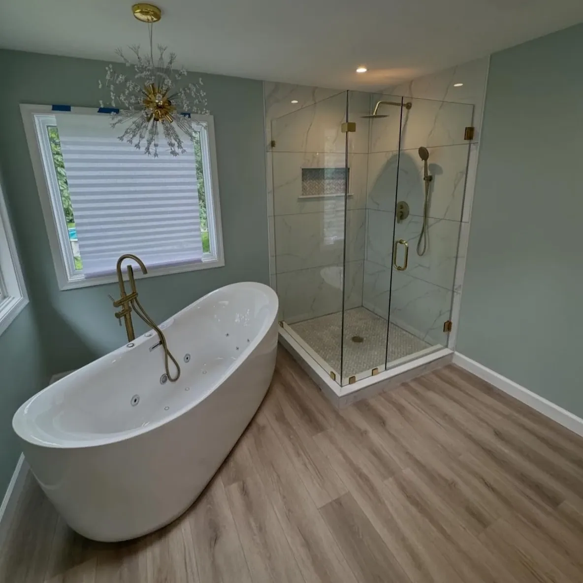 Freestanding soaking tub next to a corner glass shower in Tioga, Philadelphia