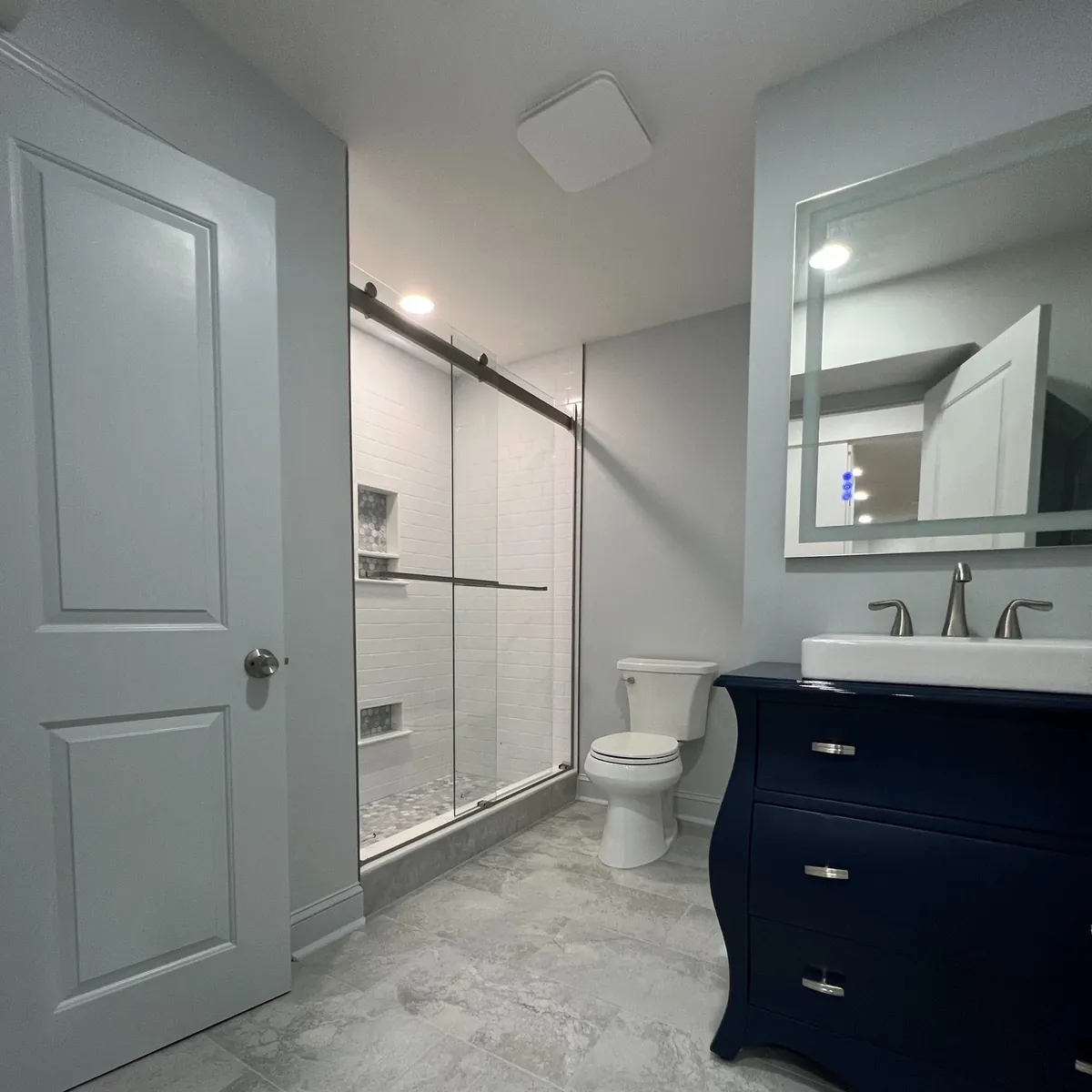 Navy vanity across from a white subway tile shower in West Oak Lane, Philadelphia