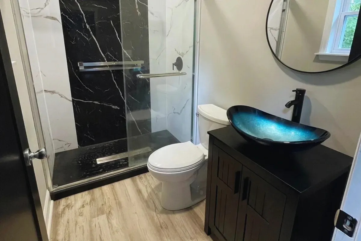 Black marble shower beside a dark vanity with a vessel sink in Wynnefield Heights, Philadelphia