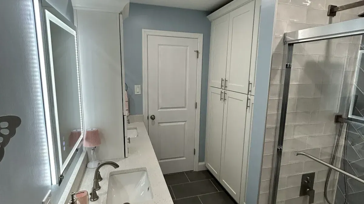Vanity with a linen tower and a glass shower enclosure in Wynnefield Heights, Philadelphia