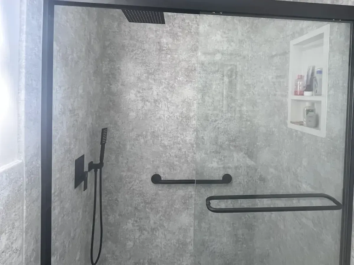 Waterproof gray stone look shower wall panels with a built-in niche, grab bar, and matte black fixtures