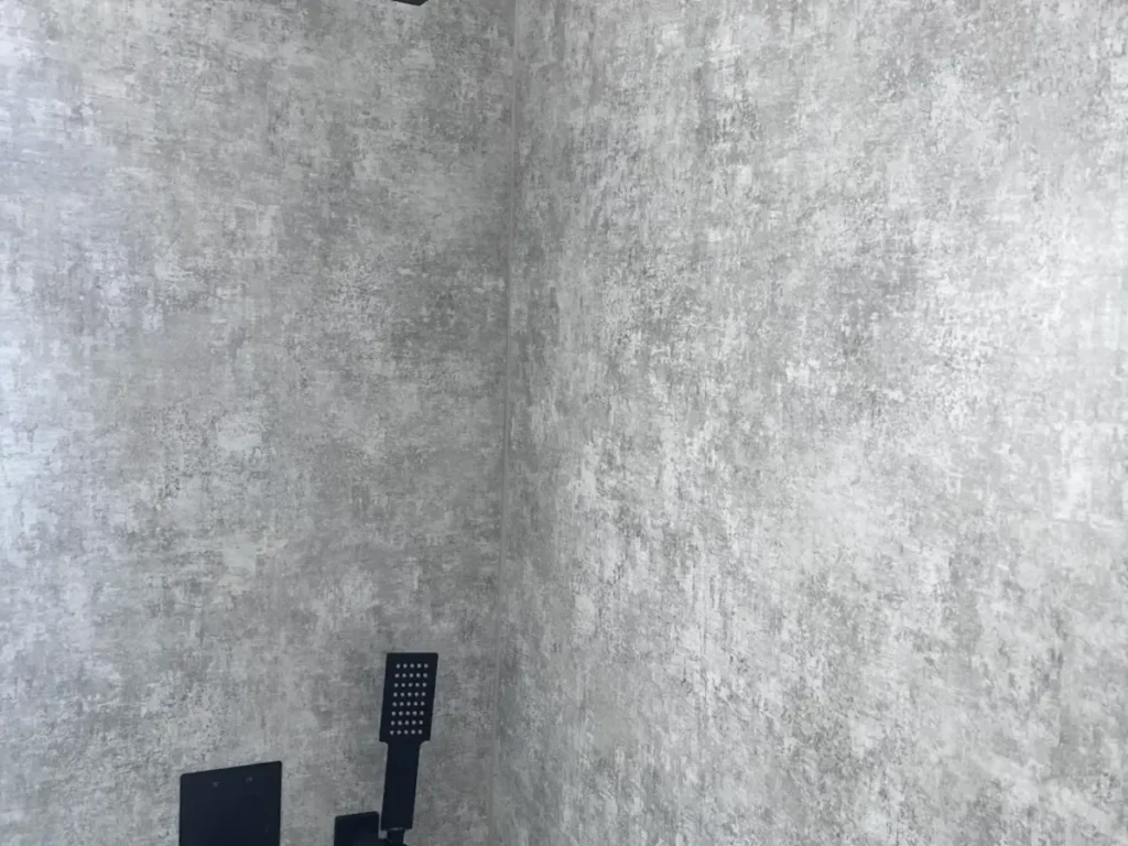New gray stone look shower wall panels with a matte black handheld shower in a replaced shower surround