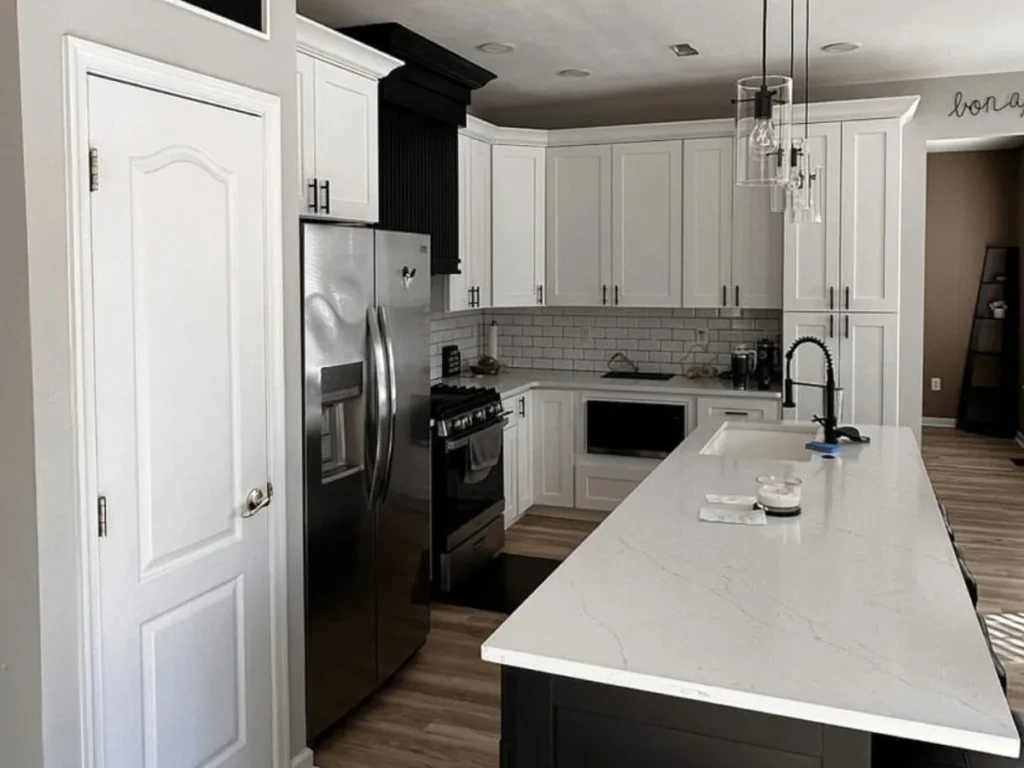Full height white pantry cabinets beside the refrigerator in a narrow Philadelphia kitchen with an island